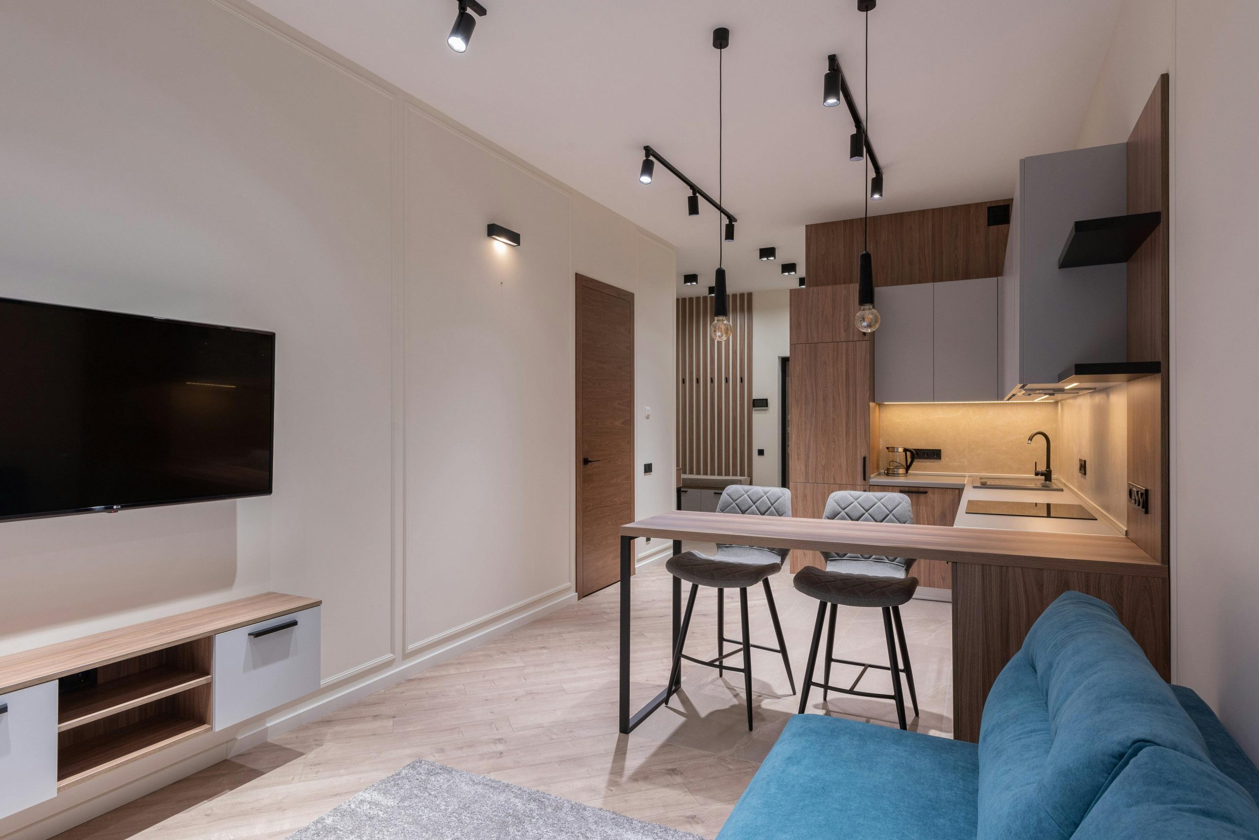 Interior of modern studio with kitchen furniture dining area and lounge with blue sofa